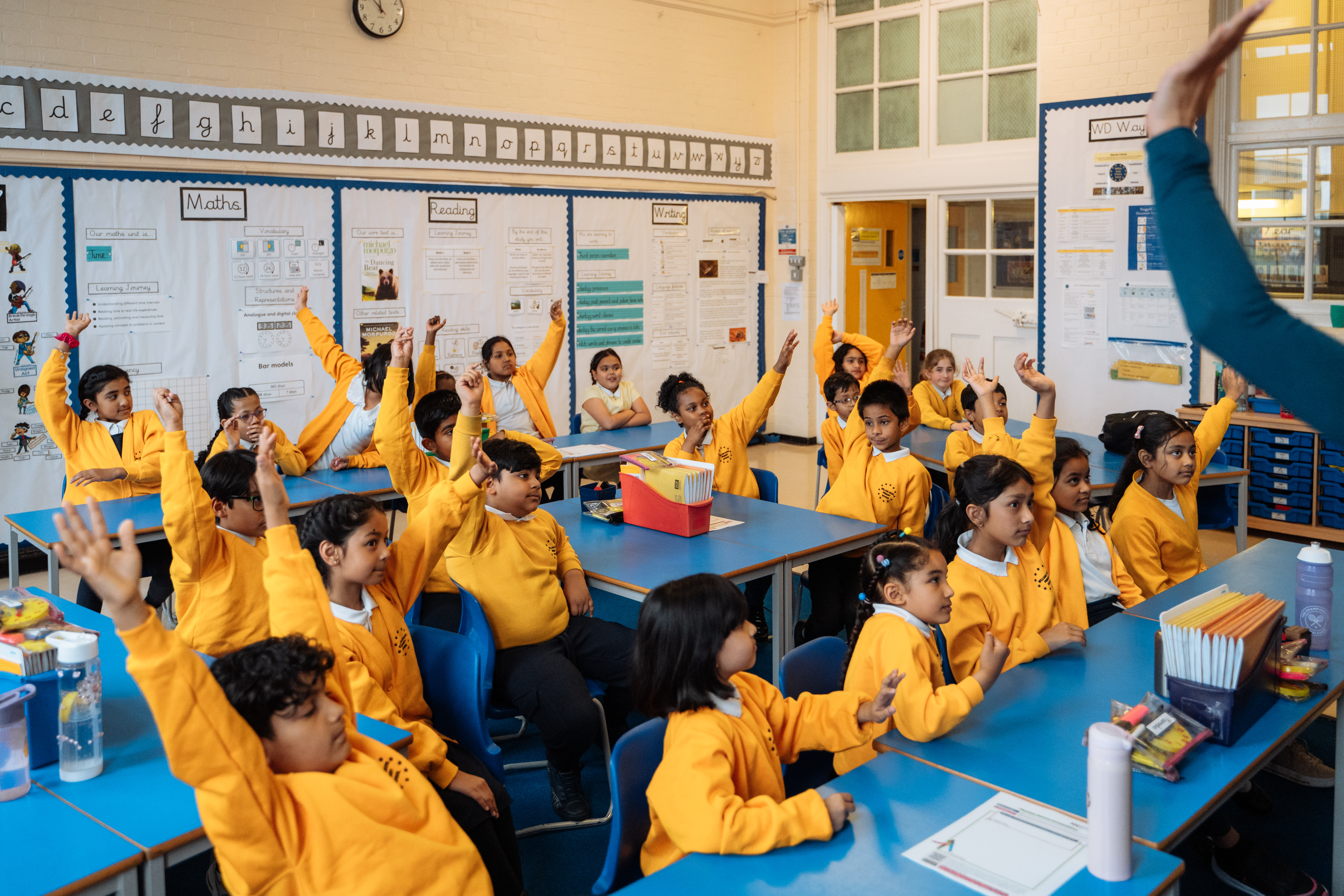 Children raising hands in class