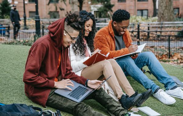 A group of people with laptops and notebooks, learning together