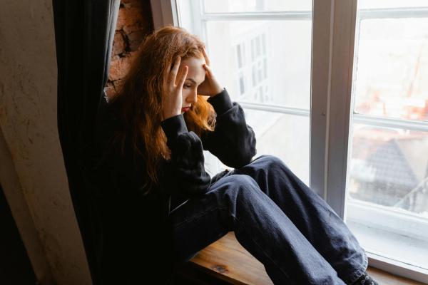 Anxious young woman sitting by a window